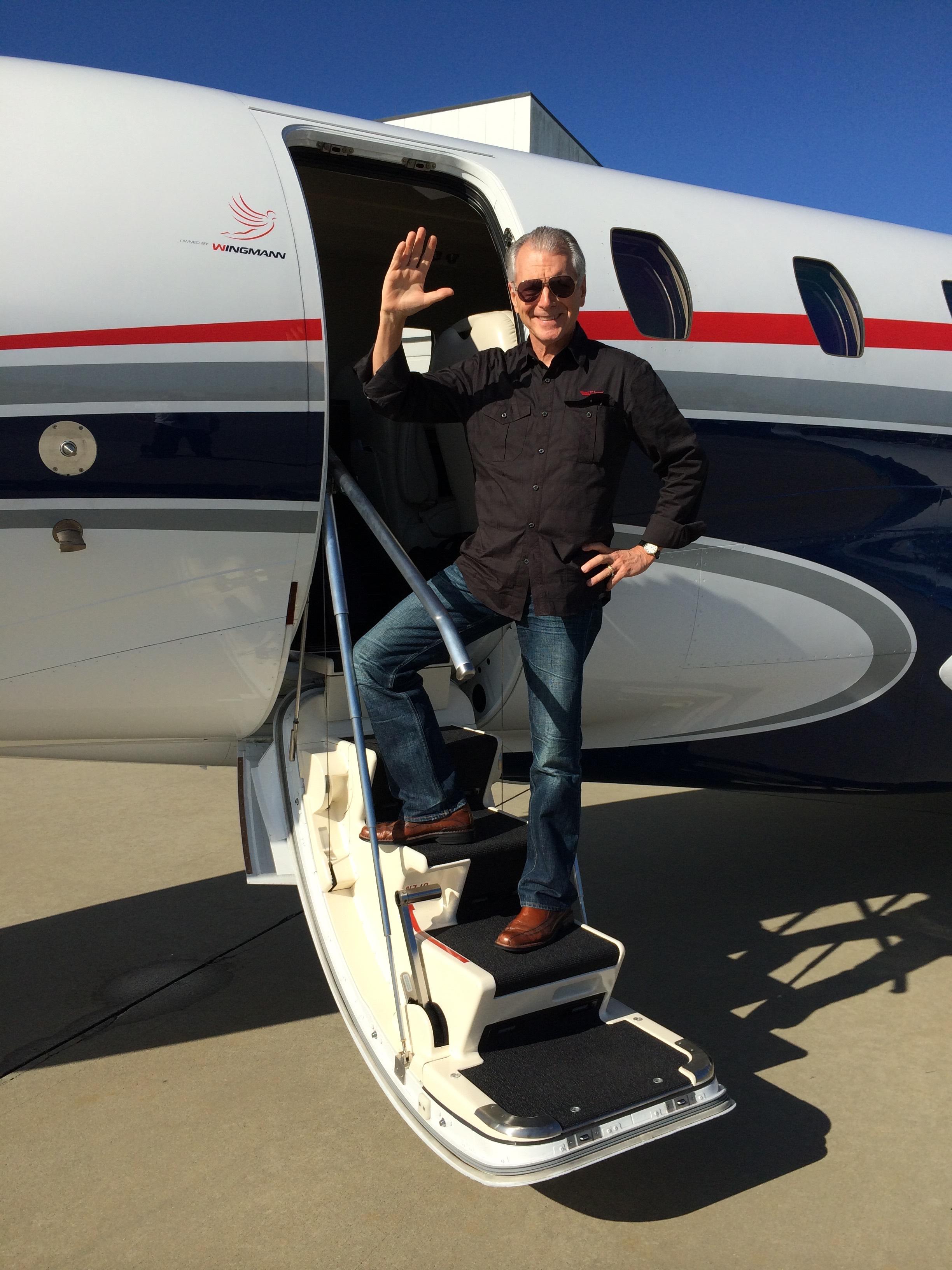 Jim Cathcart waving from a private jet