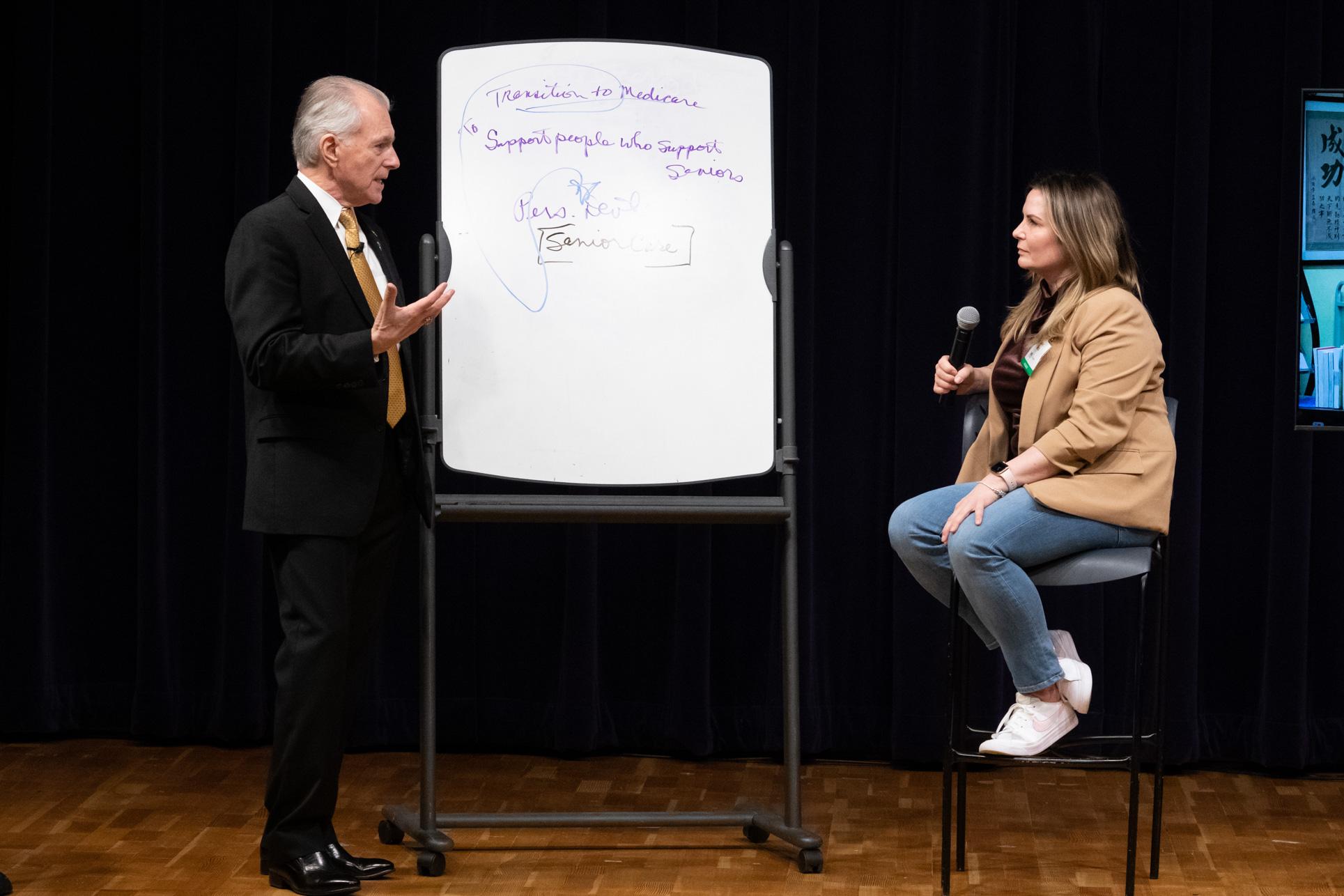 Jim Cathcart coaching a professional at the Summit, whiteboard with strategy notes visible